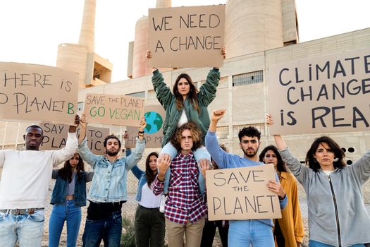 Multiracial group of people protest against climate change and plastic pollution holding signboards in the street. Demonstration to save the planet. Activist concept.