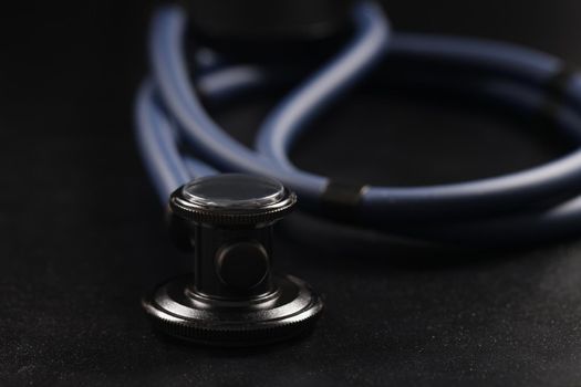 Close-up of medical stethoscope instrument on black surface, tool for patient diagnostic. Equipment for listening heartbeat and breathing. Medicine concept