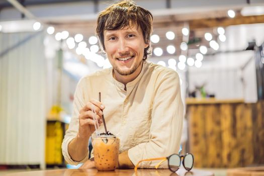 Man drinking cold bubble tea in cafe.