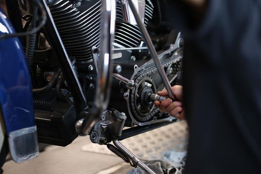 Close-up of handyman mechanic repairing part of motorbike transport with wrench equipment. Pit stop for vehicle to get fixed. Maintenance service concept