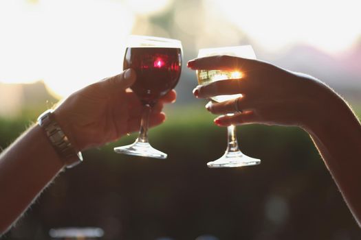 Close-up of people clinking glasses filled with wine or champagne, alcoholic drink. Couple greet, congratulate, celebrate event. Celebration, party concept