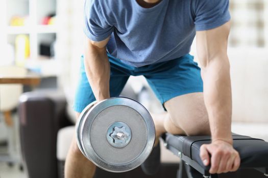 Close-up of man lifting heavy dumbbell with one hand, train body and muscles, healthy lifestyle, build own gym at home. Sport, physical activity concept