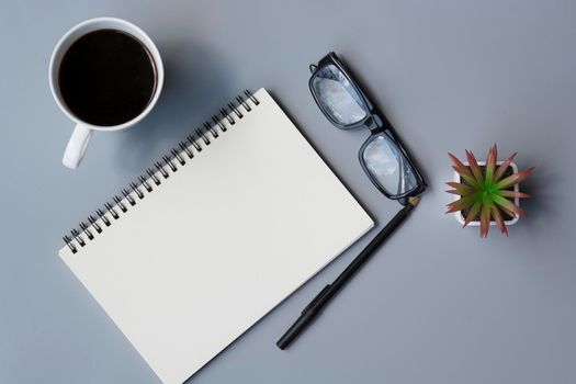 Notepad with cup of coffee and reading glasses on a desk. Directly above. Flat lay. For text usage