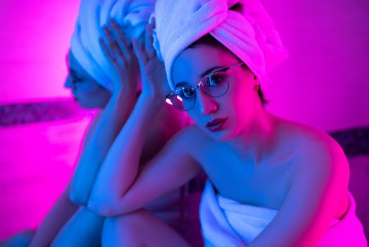 the girl with glasses with a towel in the bathroom in neon light