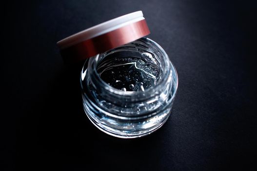 transparent jar with moisturizing gel with hyaluronic acid on a black background