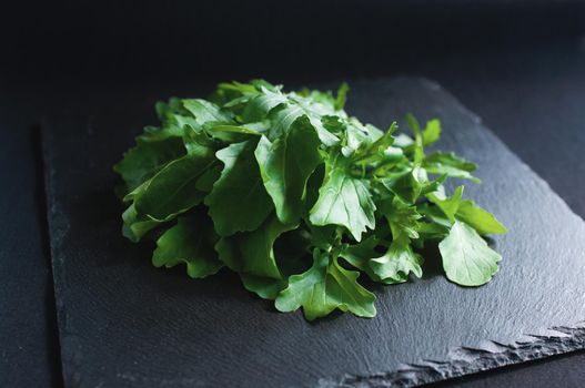 fresh arugula lying on a black board