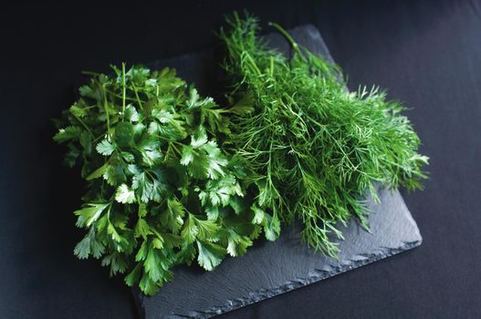 fresh dill and parsley lies on a black board