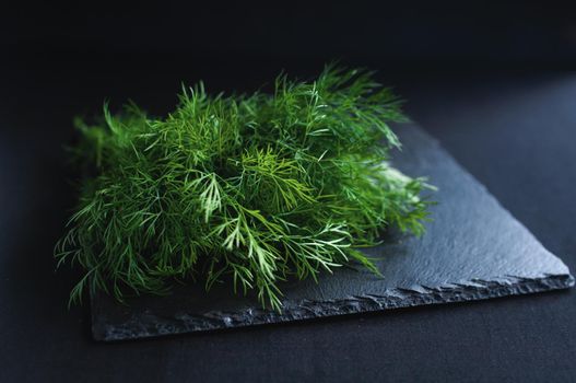 fresh dill lies on a black board