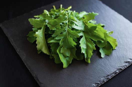 fresh arugula lying on a black board