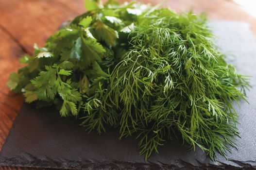 fresh arugula dill and parsley lies on a black board