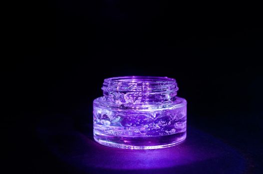 transparent jar with purple color moisturizing gel light on black background