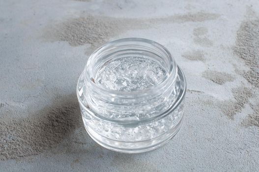 Gel with hyaluronic acid and aloe vera branches in a glass jar on a concrete background