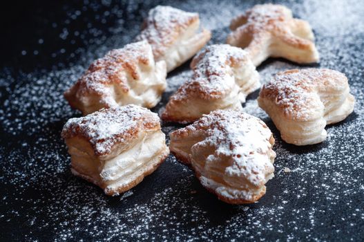 Christmas puff pastry cookies on a black slate background, sprinkled with powdered sugar