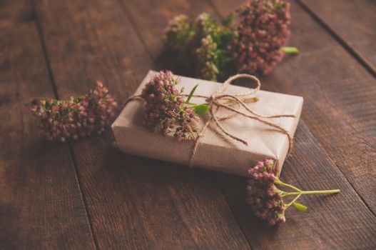 Homemade wrapped Present on a wood table. Close-up image of beautiful gift box decorated with flowers