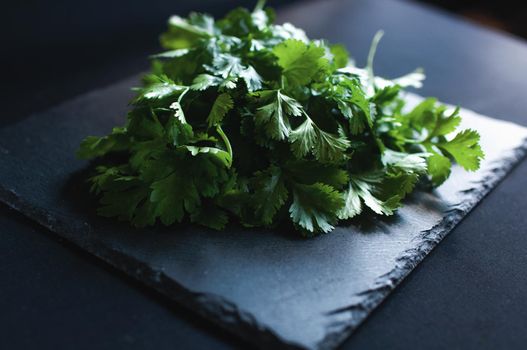 fresh dill and parsley lies on a black board