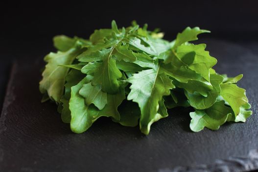 fresh arugula lying on a black board