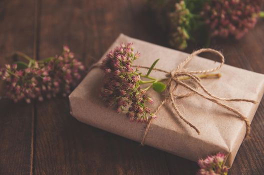 Homemade wrapped Present on a wood table. Close-up image of beautiful gift box decorated with flowers