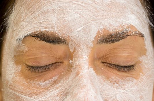 Front view of caucasian woman closed eyes and forehead with mudpack