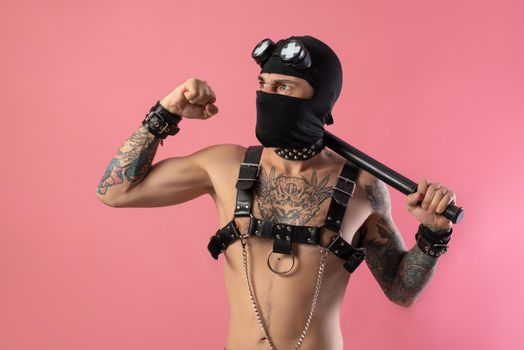 the balaclava man with leather straps on his body for bdsm sex toys with a rubber baton in his hands