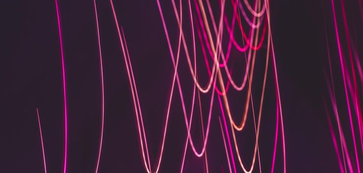 Blurred abstract light waves in purple tones on a dark background. Festive backdrop.