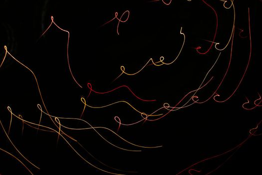 Red yellow orange curls on a black background. Abstraction. Drawing with light. Photo effect.