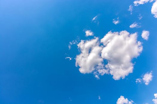 White, fluffy clouds, big and small in the blue sky. Place for text.