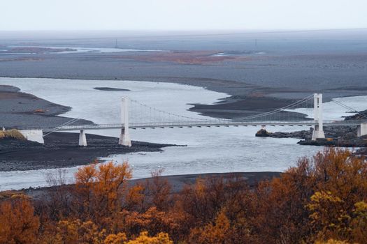 River and suspension bridge in Iceland on autumn, long shot