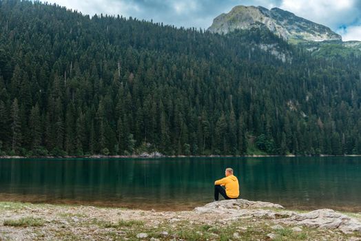 Traveler Man relaxing meditation with serene view mountains and lake landscape Travel Lifestyle hiking concept summer vacations outdoor