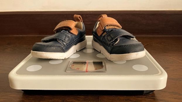 Image of toddler shoe on top of a weight scale. Weight loss concept