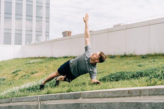 Young man has fitness workout. Male athlete does abs exercise, sport and training outdoor and stands in plank. People sport and healthy lifestyle concept.