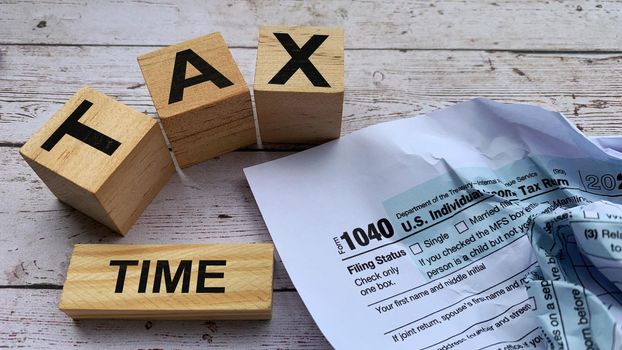 Tax time labeled on wooden blocks with tax form background.