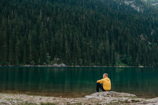 Traveler Man relaxing meditation with serene view mountains and lake landscape Travel Lifestyle hiking concept summer vacations outdoor