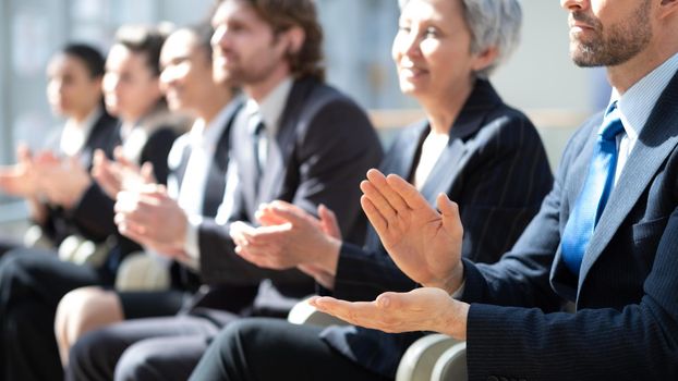 People sitting in row at business conference and applauding to speaker