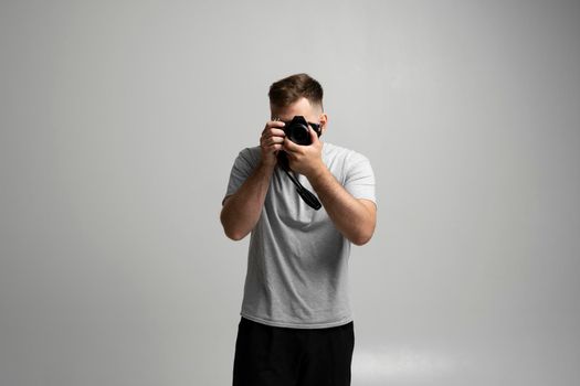 Photography, creative, artist concept. Bearded professional photographer shooting on dslr mirrorless photo camera while working in studio with a model