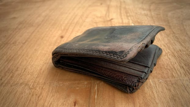 Old wallet on the wooden table. Conceptual