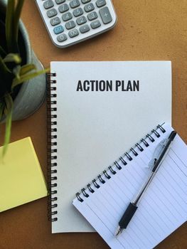 Image with action plan text on a note pad with pen, plant, calculator and sticky note. Business concept