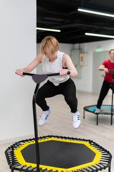 Women's and men's group on a sports trampoline, fitness training, healthy life - a concept trampoline group batut instructor men, In the afternoon lifestyle activity for gym for exercise shaping, wellness happiness. Legs beauty loss, class