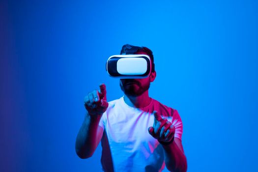 Excited bearded man experiencing virtual reality via VR headset and touching something, stretching and zooming with his hands