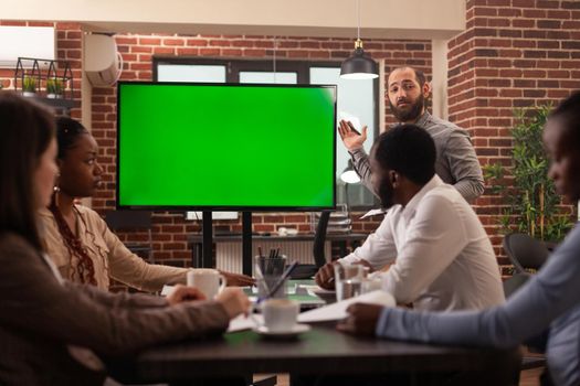 Executive manager man explaining marketing strategy using mock up green screen chroma key monitor with isolated display working in startup company office. Businesspeople brainstorming project ideas