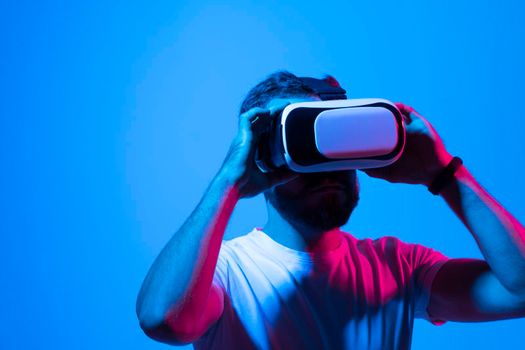 Close up portrait of amazed young bearded man, wearing high tech smart vr goggles, watching 360 degree video or playing a video game with his friends