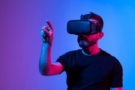 Future Technology and Business Concept. Bearded man in a black t-shirt with glasses of virtual reality touching something in a virtual space while speaking with a friends in metaverse world