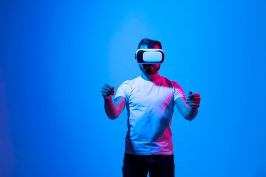 Man use a VR headset and stands as he hold something in virtual space. Future technology, online game, virtual reality, entertainment, study, 3D simulation and virtual world