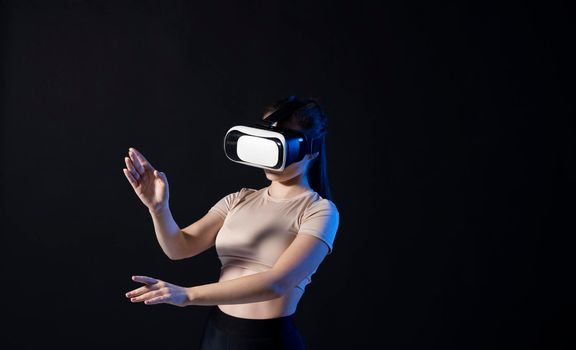 Woman architector using virtual reality glasses at workplace and working with a new project. Woman working in VR goggles in neon light. Designer working in VR studio