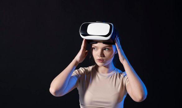 Brunette woman gamer with a virtual reality glasses ready to play a game or explore the environment in a metaverse world. Modern technologies