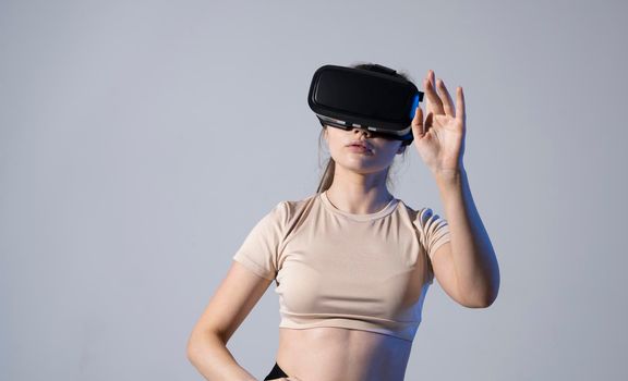 VR, augmented reality, science, future technology concept. Young brunette woman in glasses of virtual reality in neon light. Futuristic 3d glasses with virtual projection