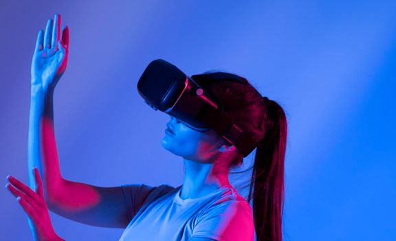 Woman experiencing virtual reality goggles in neon light