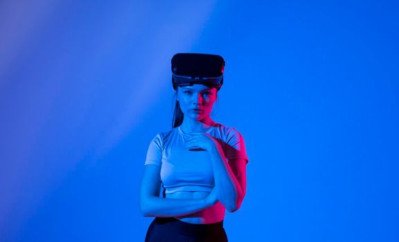 Beautiful brunette woman gamer with a virtual reality glasses ready to play a game in neon light. Modern technologies