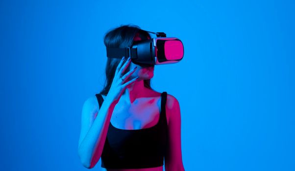 Young woman in a black t-shirt using the VR goggles and communicating with friends in a metaverse social network. Future technology concept