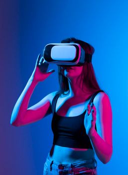 Young woman using VR headset helmet and interacts with a friends in metaverse social network using swipe and stretching gestures. She watching virtual reality 3d video with a friends