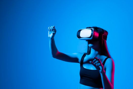 Brunette woman in a black t-shirt in VR headset looking up at the objects in virtual reality while playing a game or watching 3d movie and trying to touch it. Future technology concept